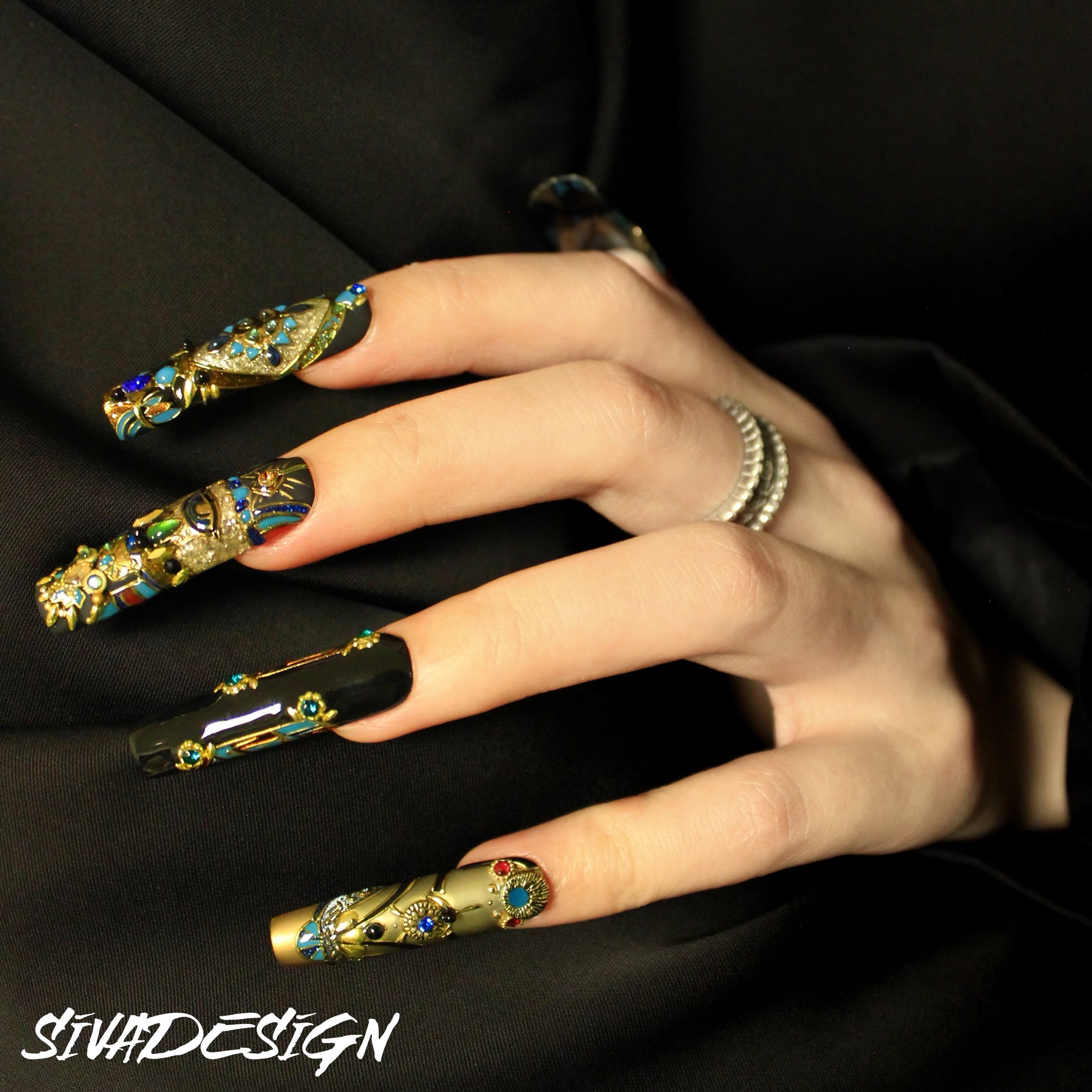 Luxurious black and gold press-on nails with intricate gemstone designs and metallic accents